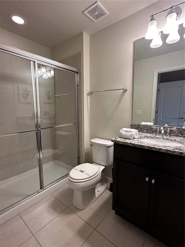 bathroom with tile patterned floors, walk in shower, vanity, a textured ceiling, and toilet