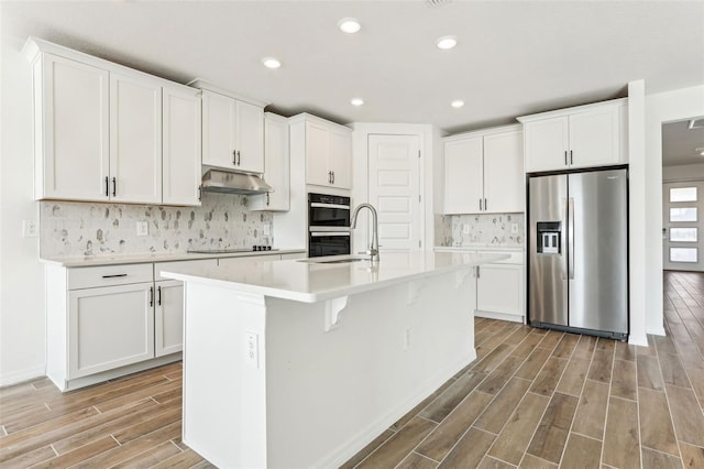 kitchen with sink, white cabinets, black appliances, and a center island with sink