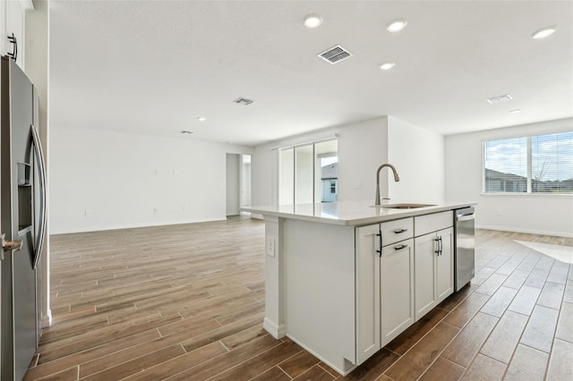 kitchen featuring a center island with sink, white cabinets, sink, and stainless steel appliances