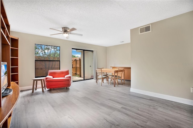 sitting room with ceiling fan, wood-type flooring, and a textured ceiling