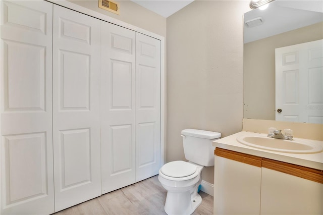 bathroom with wood-type flooring, toilet, and vanity