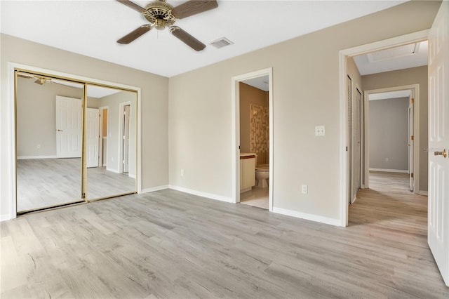 unfurnished bedroom with ceiling fan, a closet, light wood-type flooring, and connected bathroom