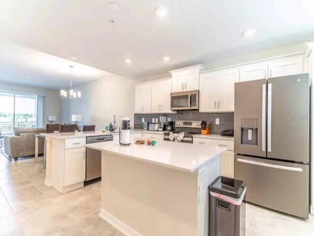 kitchen with a peninsula, stainless steel appliances, light countertops, open floor plan, and tasteful backsplash