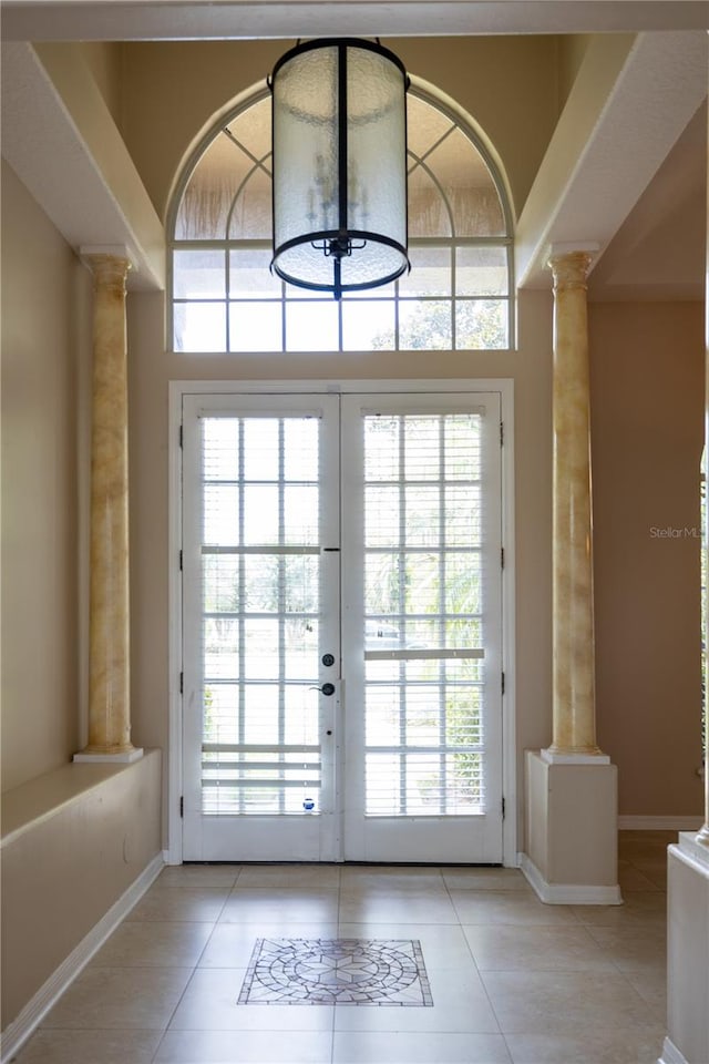 doorway to outside with decorative columns, a high ceiling, light tile patterned floors, and french doors