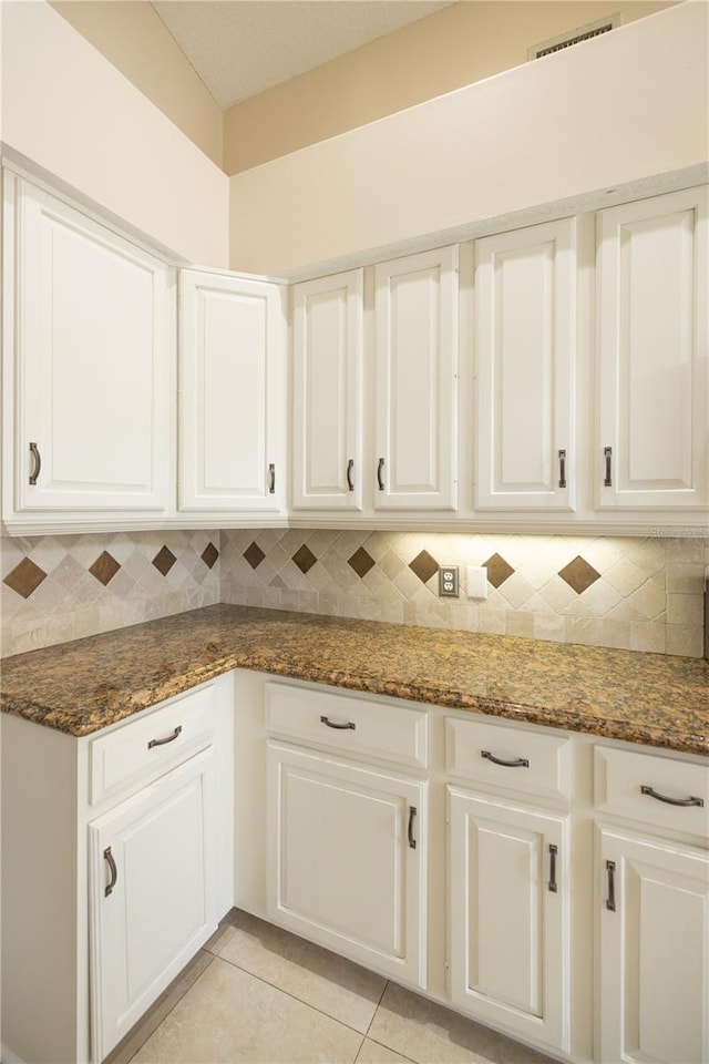 kitchen featuring dark stone counters and white cabinets