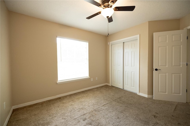 unfurnished bedroom with carpet flooring, a textured ceiling, ceiling fan, and a closet