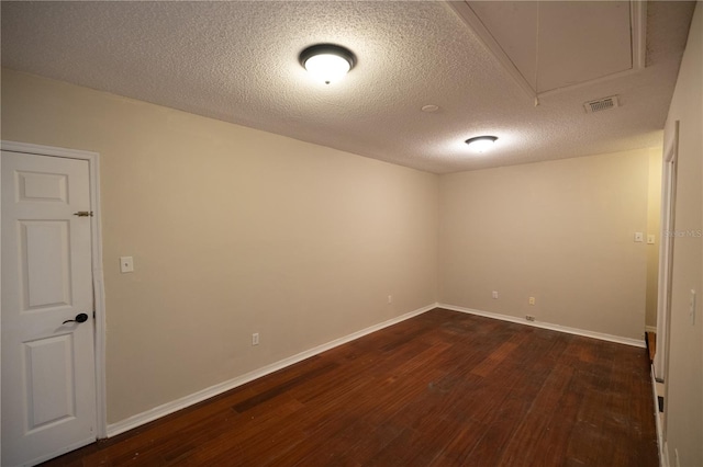 spare room featuring dark hardwood / wood-style floors and a textured ceiling