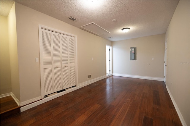 unfurnished bedroom with dark wood-type flooring, electric panel, a closet, and a textured ceiling