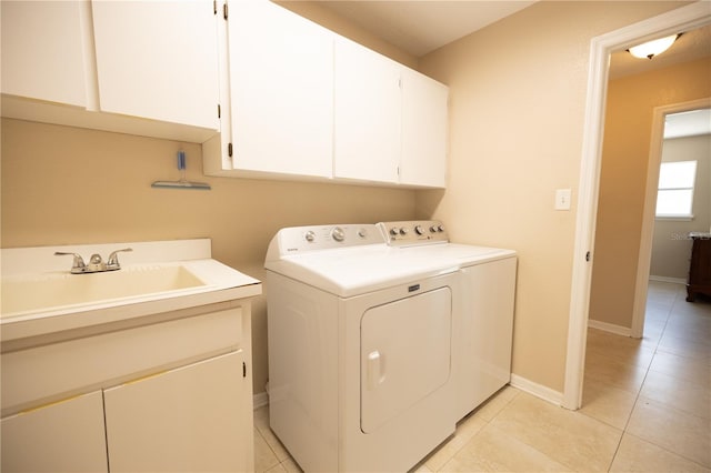 washroom with cabinets, sink, washing machine and dryer, and light tile patterned floors