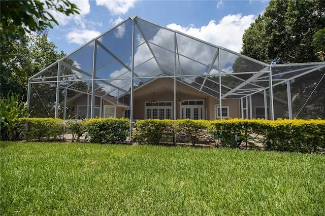 back of house with a lawn and glass enclosure