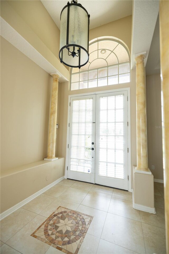 doorway to outside with light tile patterned floors and decorative columns