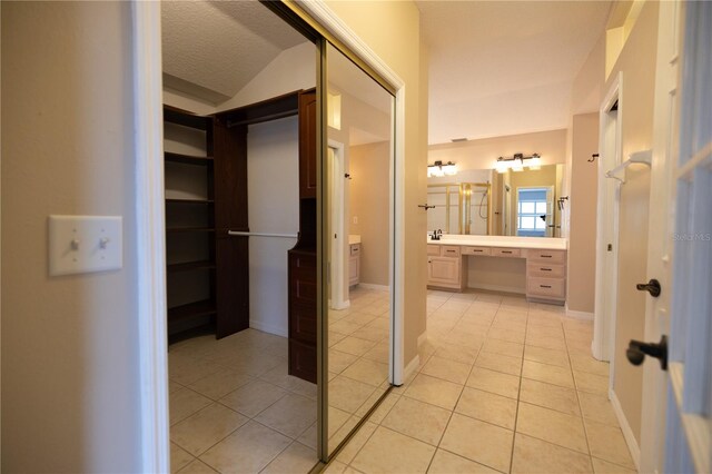 bathroom with vanity, lofted ceiling, tile patterned floors, and a textured ceiling