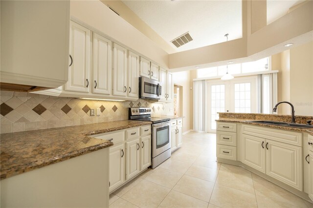 kitchen featuring sink, dark stone countertops, backsplash, light tile patterned floors, and stainless steel appliances