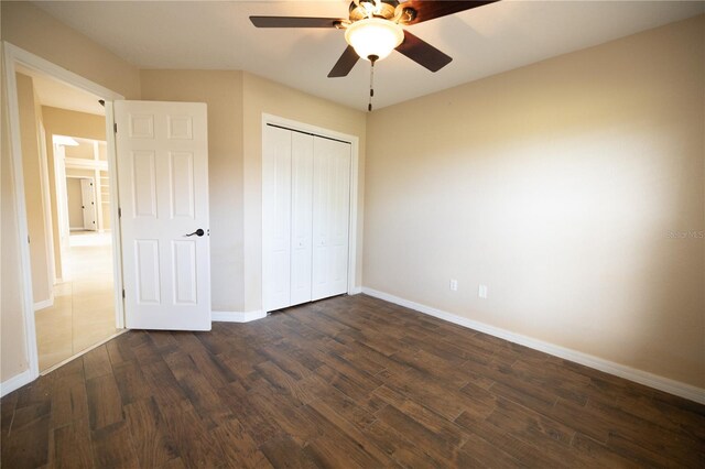 unfurnished bedroom with ceiling fan, dark hardwood / wood-style flooring, and a closet