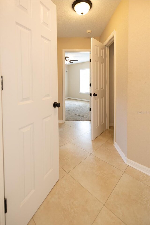 corridor featuring light tile patterned floors and a textured ceiling