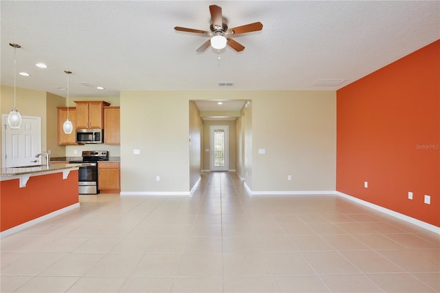 kitchen with pendant lighting, light tile patterned floors, ceiling fan, appliances with stainless steel finishes, and a kitchen breakfast bar