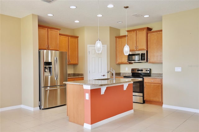 kitchen with sink, a center island with sink, light tile patterned floors, appliances with stainless steel finishes, and light stone countertops