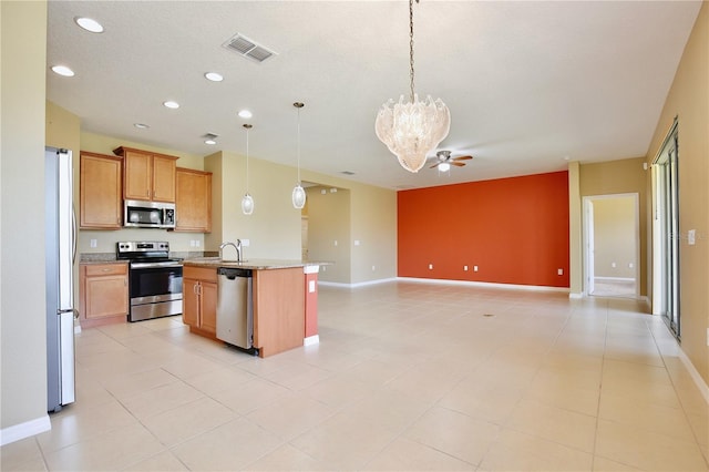 kitchen with sink, ceiling fan with notable chandelier, stainless steel appliances, a center island with sink, and decorative light fixtures