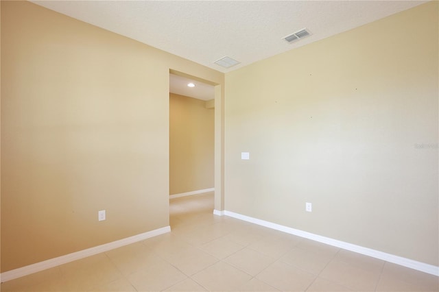 empty room featuring light tile patterned floors and a textured ceiling