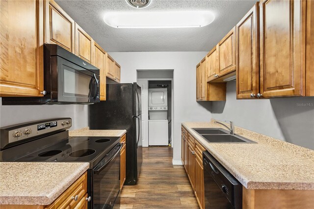 kitchen featuring sink, stacked washer / dryer, black appliances, a textured ceiling, and dark hardwood / wood-style flooring