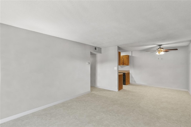 unfurnished living room featuring light carpet, ceiling fan, and a textured ceiling