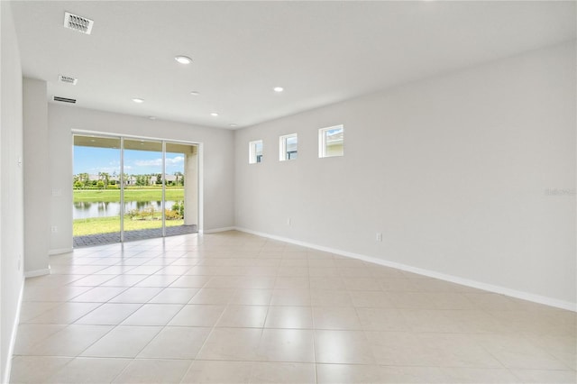 spare room with a water view and light tile patterned flooring