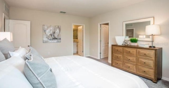 bedroom featuring ensuite bathroom and light colored carpet