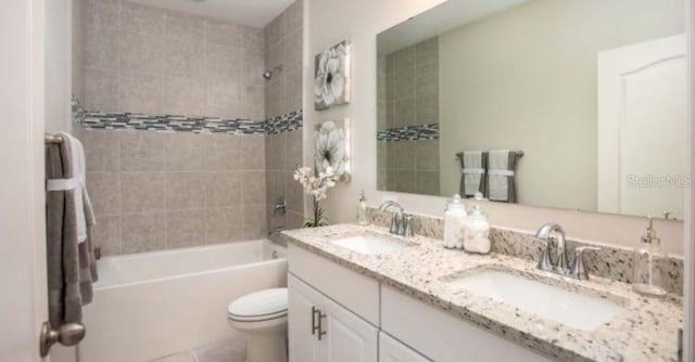 full bathroom with toilet, tiled shower / bath, and vanity