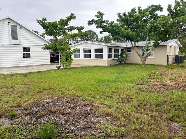 rear view of house featuring a patio area, fence, central AC unit, and a yard