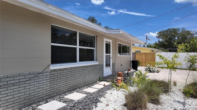 view of home's exterior with fence and brick siding