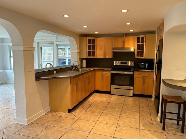 kitchen with black appliances, dark countertops, glass insert cabinets, and under cabinet range hood