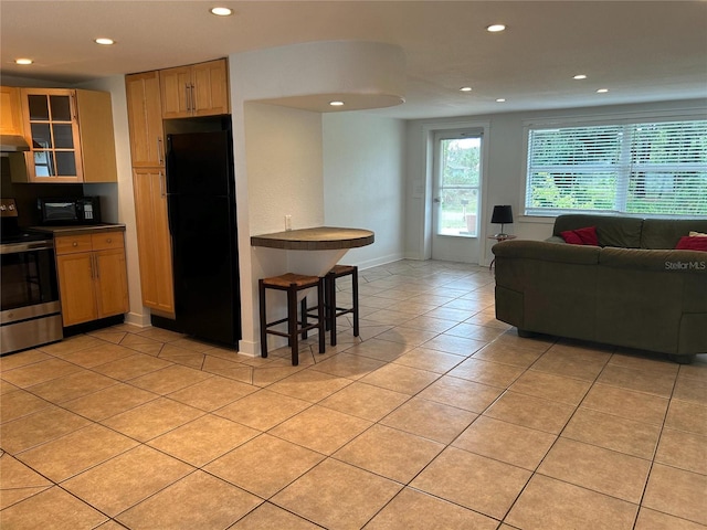 kitchen featuring light tile patterned floors, dark countertops, glass insert cabinets, open floor plan, and black appliances