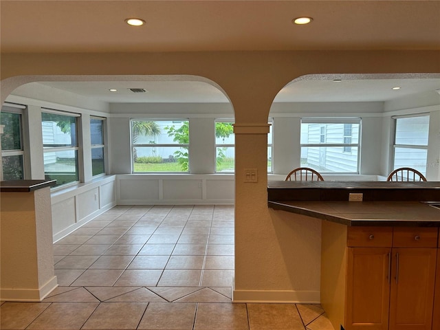 kitchen with recessed lighting, dark countertops, light tile patterned flooring, and brown cabinets