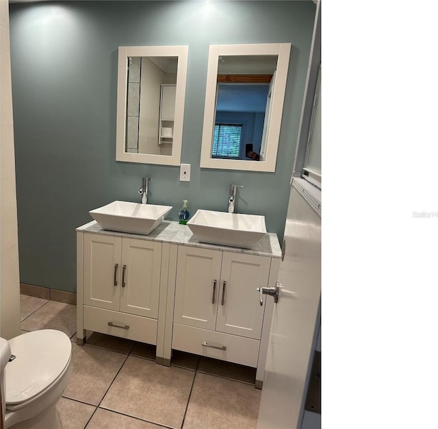 bathroom featuring double vanity, tile patterned flooring, toilet, and a sink