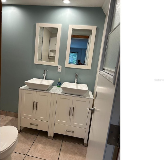 bathroom featuring toilet, tile patterned flooring, double vanity, and a sink