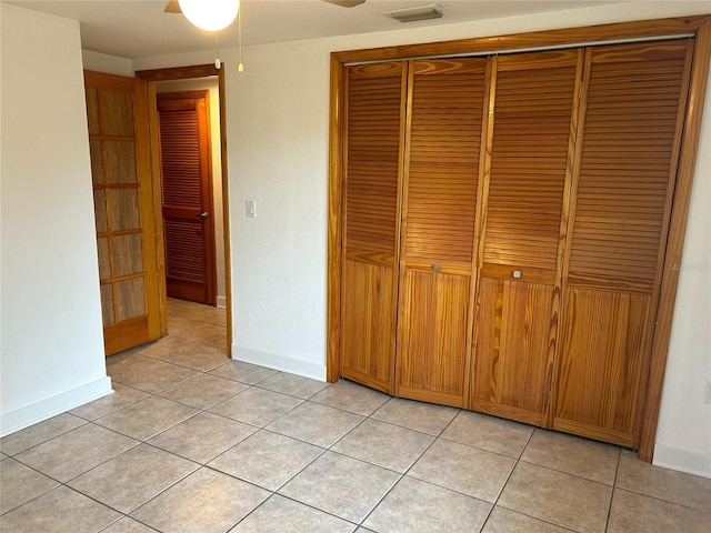 unfurnished bedroom with light tile patterned floors, a closet, visible vents, and baseboards