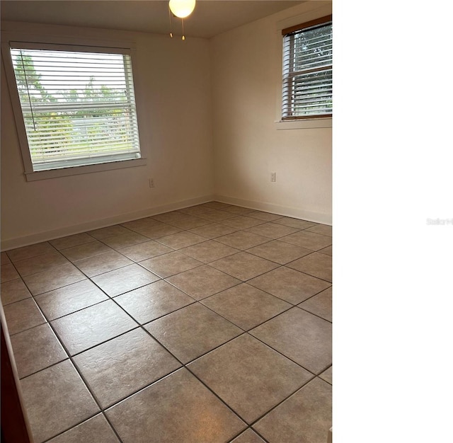 spare room featuring baseboards and light tile patterned floors