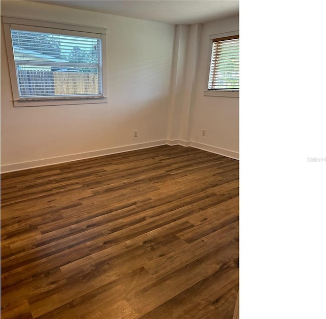 spare room with dark wood finished floors and baseboards