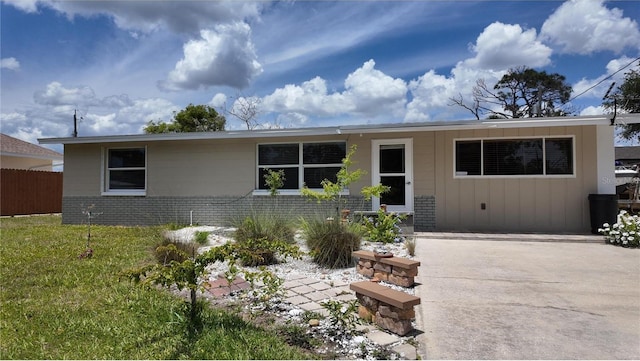 ranch-style house featuring a front yard, fence, board and batten siding, and brick siding