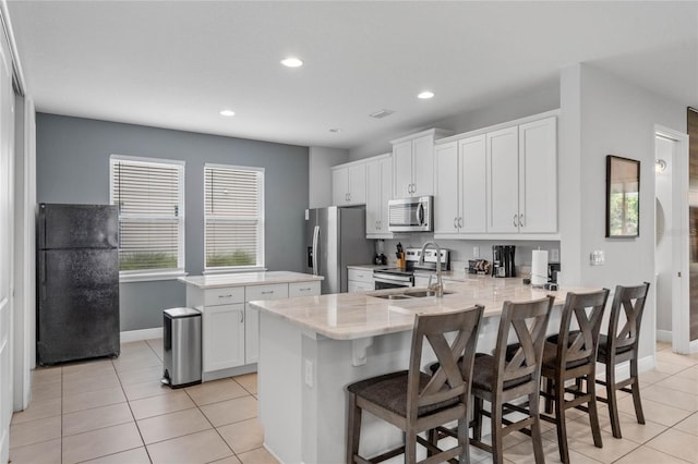 kitchen with kitchen peninsula, stainless steel appliances, white cabinetry, and a wealth of natural light