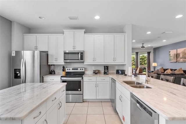 kitchen featuring white cabinetry, sink, kitchen peninsula, light tile patterned floors, and appliances with stainless steel finishes