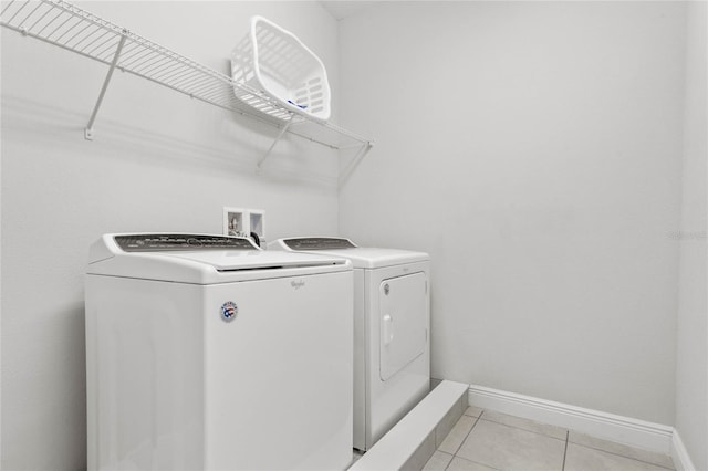 laundry area with independent washer and dryer and light tile patterned floors