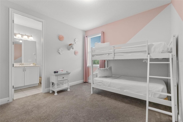 bedroom featuring ensuite bathroom and light colored carpet