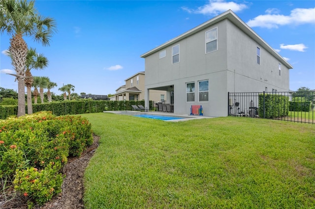 rear view of property featuring a fenced in pool and a yard