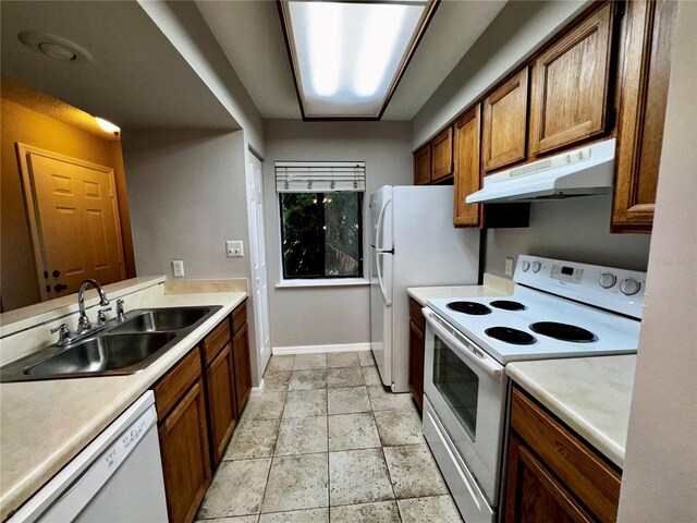 kitchen featuring sink, white appliances, and light tile flooring