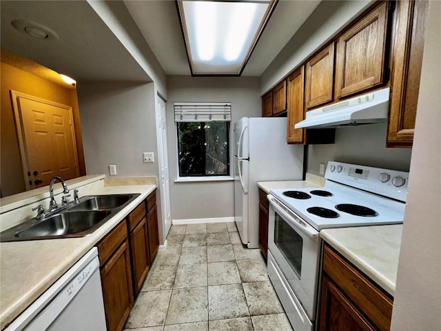 kitchen with under cabinet range hood, white appliances, a sink, and light countertops