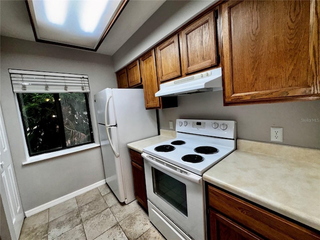 kitchen with under cabinet range hood, baseboards, white appliances, and light countertops