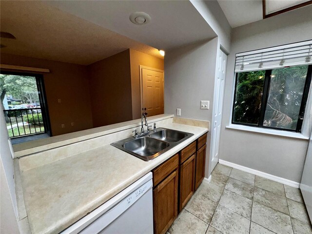 kitchen featuring sink, white dishwasher, and light tile floors