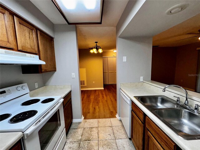 kitchen featuring sink, an inviting chandelier, light tile flooring, and white appliances