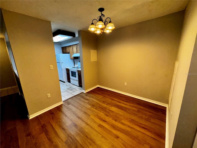 unfurnished room with an inviting chandelier, a textured ceiling, and light wood-type flooring